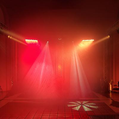 Proiezione scenografica con fasci di luce rossa e gialla su fumo teatrale, impianto luci dinamico per eventi - by Disco Express