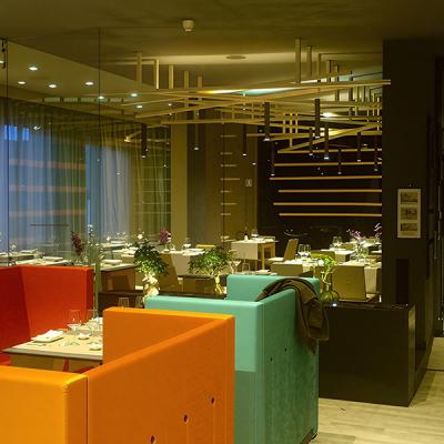 Ristorante moderno con arredi colorati e illuminazione d’ambiente integrata a soffitto - progetto di impiantistica estetica e funzionale